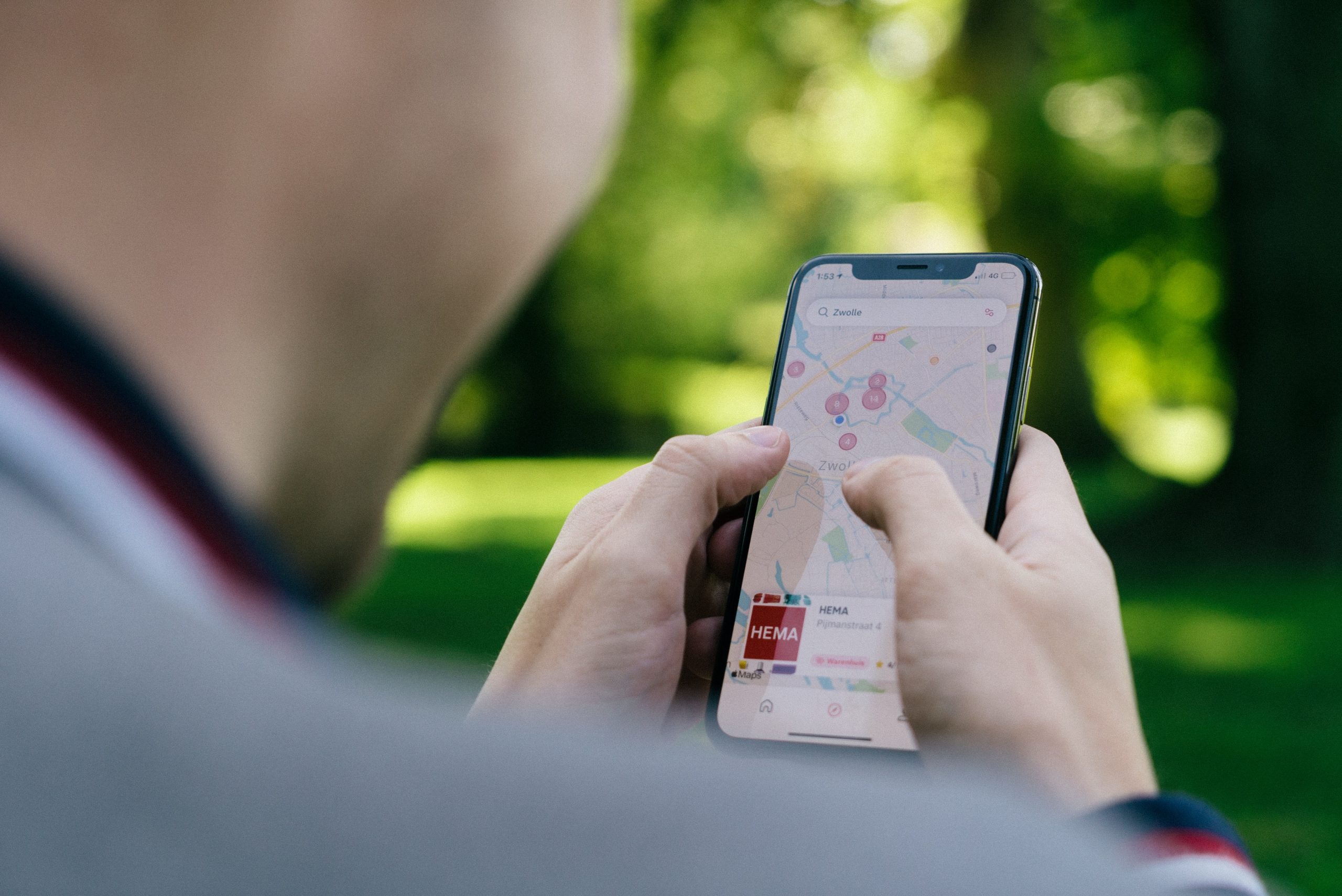 A photograph of a man using an iPhone to look at Google maps