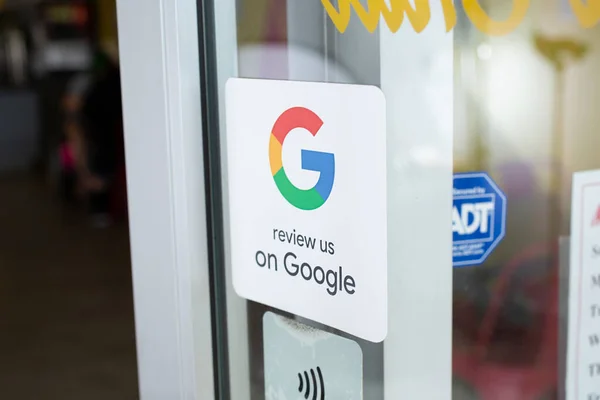 A sticker on a shop window of the Google logo encouraging visitors to leave a Google review