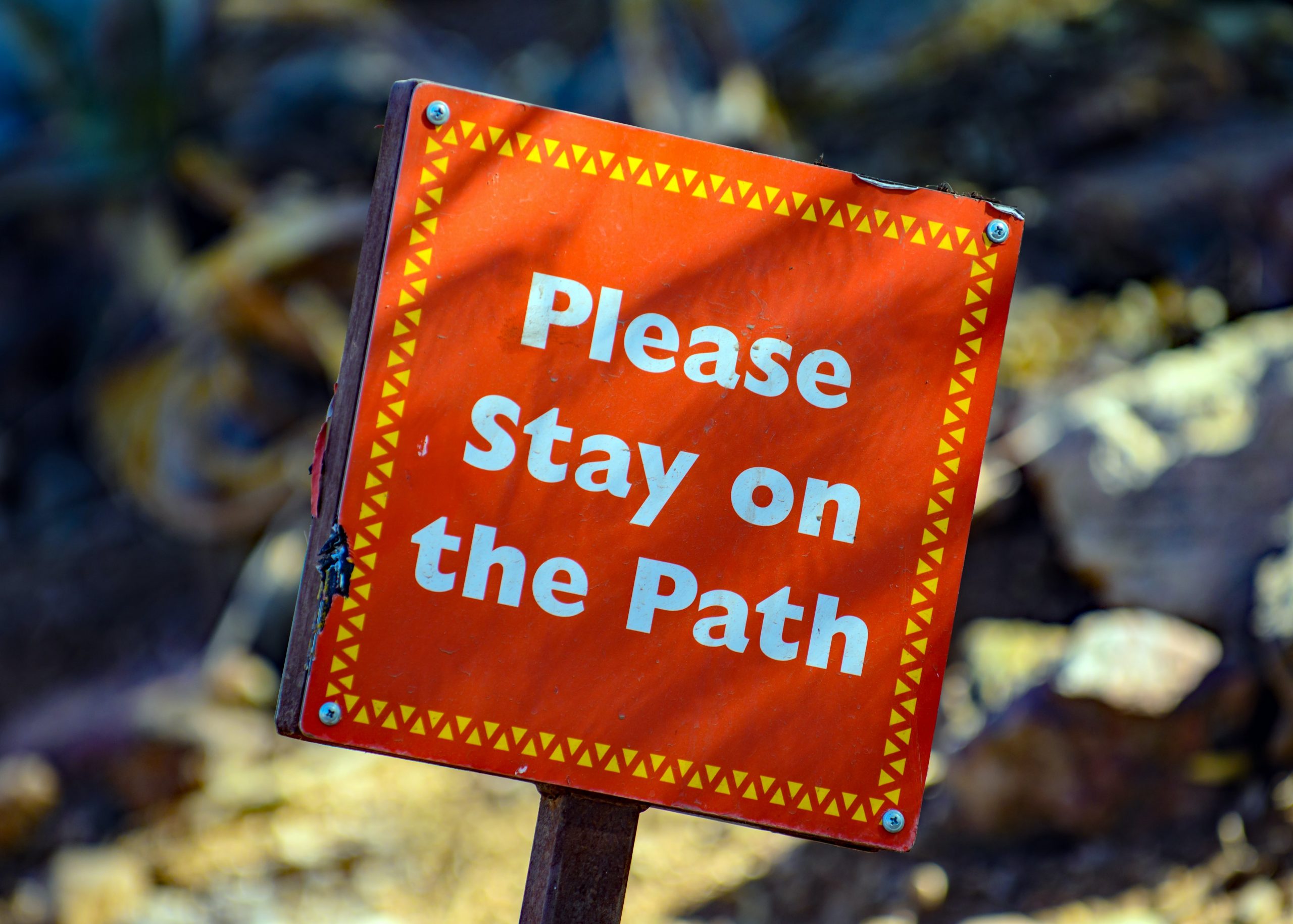 A sign that says please stay on the path