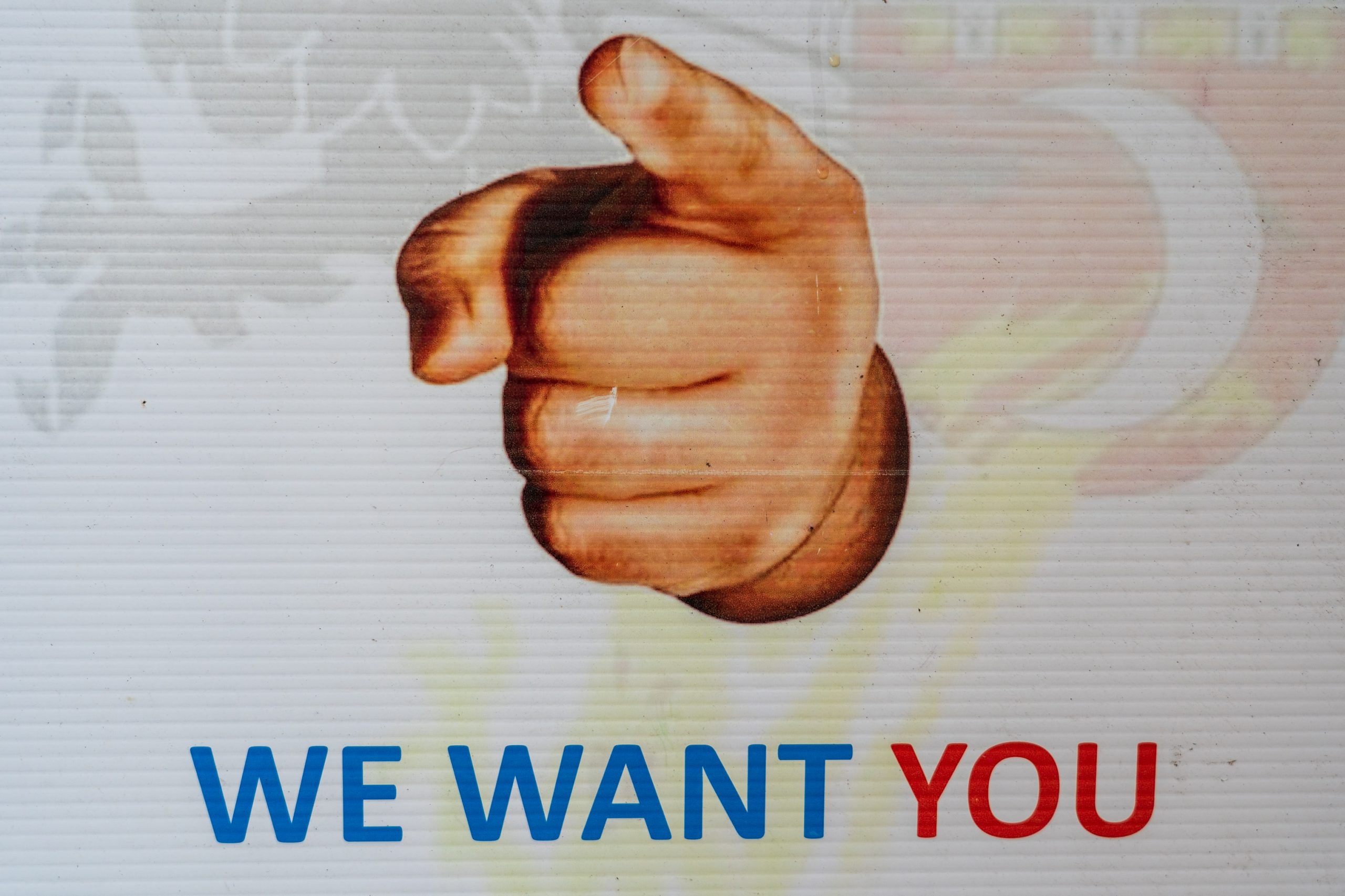 A close up of a poster that says we want you with a giant finger pointing at the viewer