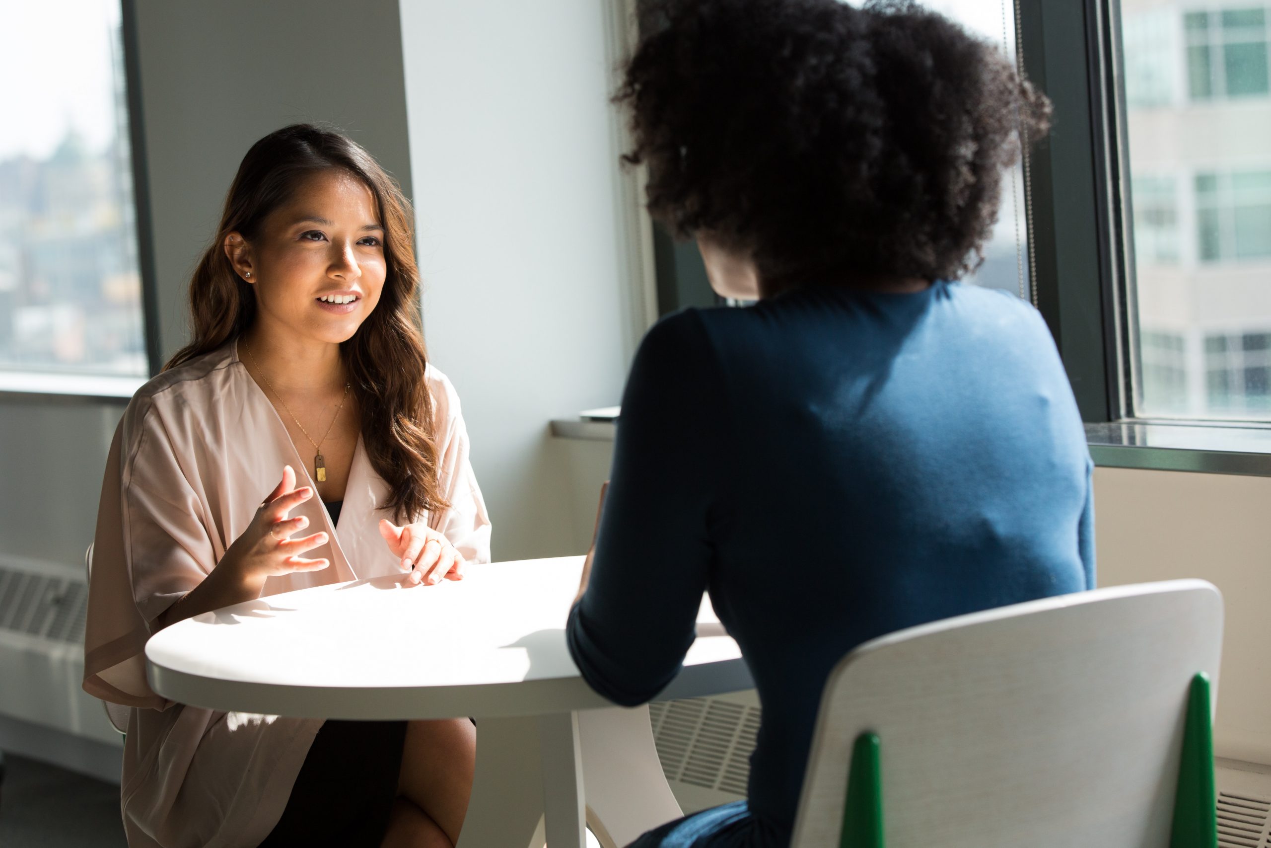 Two women talking at a table in an office