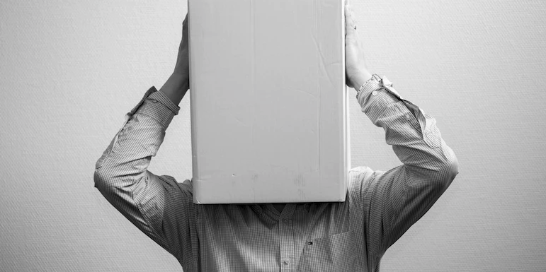 A black and white image of a man with a box on his head